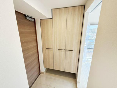 玄関は明るい雰囲気で清潔感があります。収納スペースがあり整理整頓もしやすそうです。落ち着いた色合いの扉が空間を引き締めています。タイル床でお手入れも簡単です。