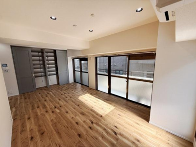 壁面に収納スペースが設けられたお部屋です。大きな窓から光が差し込み明るさが魅力の空間です。床の木目調が温かみを感じさせます。クローゼットは開口が広く使い勝手に配慮されています。