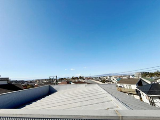 広がる青空と街並みを望むことができる現地からの眺望です。遠くまで視界が開けており周囲の開放感が魅力です。屋根の向こうに広がる景色が印象的で視覚的な広がりを感じられます。