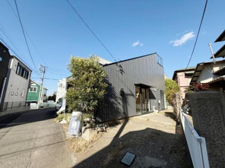 現地の前面道路はすっきりとした印象です。周囲には住宅が立ち並び落ち着いた雰囲気が感じられます。建物の外観もスタイリッシュなデザインとなっています。敷地へのアクセスも分かりやすいです。