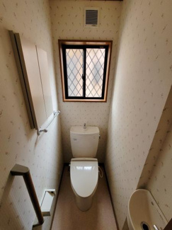 窓があり換気しやすいトイレです。手すりが設置されていて安心して利用いただけます。棚やペーパーホルダーも備わっています。シンプルな内装でお手入れも簡単です。