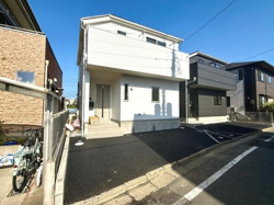 シンプルで整った外観が特徴の建物です。前面道路は幅もあり車の出入りもスムーズです。周囲の住宅とも調和した雰囲気が感じられます。爽やかな青空のもとで開放的な現地写真となっています。
