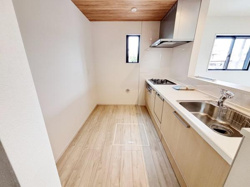 木目調の天井と床が調和したキッチンです。カウンターが広く作業がしやすい空間になっています。窓が2カ所にあり自然光が入りやすくなっています。換気もしやすいレイアウトです。