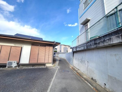 広々とした道路に面しており車両の出入りがしやすい環境です。周囲は静かな雰囲気で落ち着いた暮らしが期待できます。建物の外観も整っており安心感があります。晴れた日の空が広がり開放的な印象です。