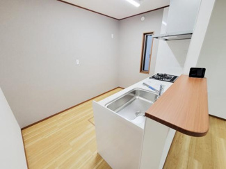 シンプルな内装が特徴のキッチンです。床材の風合いが全体を明るく演出しています。窓があり自然光を取り入れることができます。手元を広く使えるカウンターも備わっています。