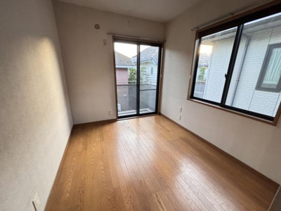 二面の窓から自然光が差し込む洋室です。木目のフローリングが優しい雰囲気を演出しています。落ち着いた空間が広がっています。バルコニーへアクセス可能です。使い勝手の良い形状も魅力です。