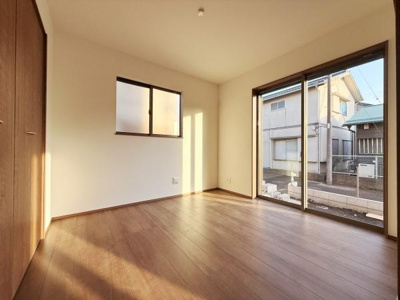 大きな窓から光が差し込む洋室です。床は木目調で温かみがありシンプルな壁面が空間を広く感じさせます。収納スペースも備わっており暮らしやすい設計となっています。バルコニーへのアクセスも便利です。