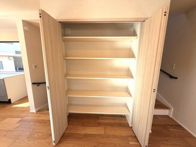 シンプルなデザインの収納スペースが特徴です。扉付きで中身をすっきり隠すことができます。棚の高さが調整でき多様な用途に対応します。木目調の仕上げが空間に調和しています。