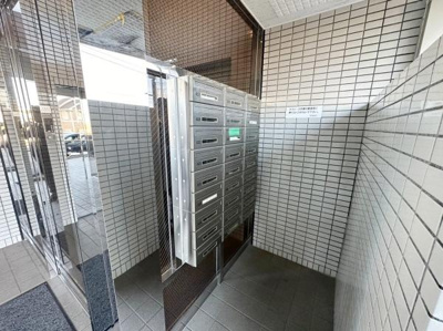 集合ポストがエントランスに配置されており郵便物の受け取りがしやすい環境です。清潔感のあるタイル壁とガラス扉が印象的です。エントランス部分が明るく管理の行き届いた雰囲気が感じられます。