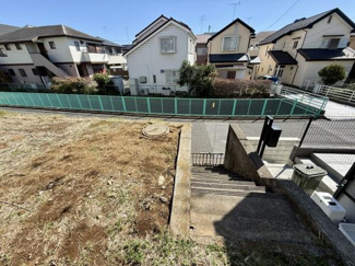現地土地写真では陽当たりの良い開放的な雰囲気が感じられます。周囲は住宅街で整った街並みが広がっています。道路との高低差が見られ階段が設置されているのが特徴的です。