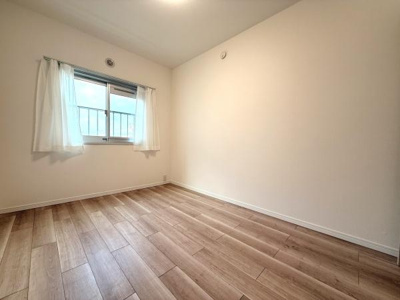 ナチュラルなフローリングが印象的な洋室です。シンプルな白壁で自由なレイアウトが楽しめます。採光性のある窓が明るさを確保しています。落ち着いた雰囲気の空間です。
