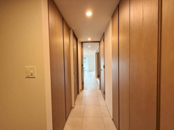 明るい照明が廊下をやさしく照らしています。ナチュラルな木目調の建具が落ち着いた雰囲気を演出します。すっきりとしたデザインで空間全体が広く感じられます。収納スペースも豊富に確保されています。