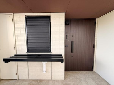 スタイリッシュなデザインの玄関が印象的です。落ち着いた色合いのドアが空間を引き締めています。フラワーボックスが設置されています。タイル張りの壁面が清潔感を演出しています。