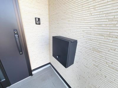 玄関にはシンプルで落ち着いたデザインの外壁が使われています。モダンな黒色のドアと宅配ボックスが調和しています。玄関スペースが広くすっきりとした印象です。