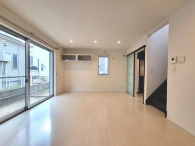 リビングには大きな窓があり開放感を感じられます。天井に設置されたダウンライトが空間を明るく照らします。収納棚が備え付けられており便利に活用できます。フローリングの色味が室内をすっきりと見せます。