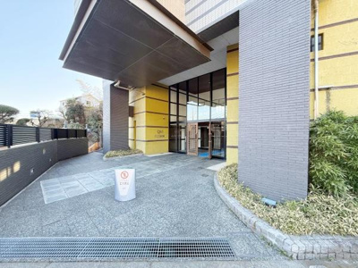 広々とした玄関アプローチは日々の出入りがしやすく印象的です。ガラス扉から明るい光が差し込み開放感を感じられます。屋根付きの設計により天候を気にせず利用できます。建物と植栽の調和も魅力です。