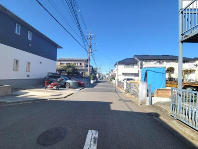 前面道路が広々としており車の出し入れがしやすい環境です。住宅街の落ち着いた雰囲気が感じられます。周辺には戸建てが並び静かな街並みを実感できます。車やバイクなどの駐車スペースもしっかり確保されています。