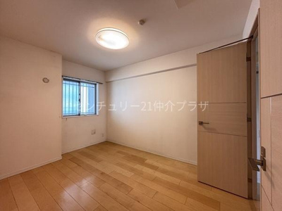 ナチュラルな色合いのフローリングが空間を引き立てています。窓からは自然光が差し込み明るさが感じられます。ドアや壁もシンプルなデザインで洋室全体がすっきりとした印象です。