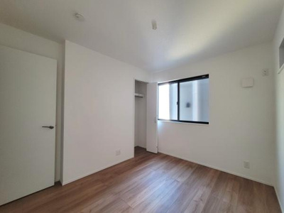 白を基調とした洋室には大きな窓からやわらかな光が差し込みます。シンプルな内装があらゆるインテリアと相性がよいです。収納スペースも確保されています。木目調の床が落ち着いた雰囲気を演出しています。