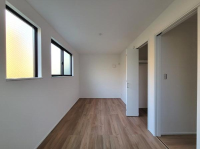 洋室は窓からの採光がしっかり確保されており明るい印象です。白を基調とした壁が清潔感を演出しています。収納スペースも備えておりすっきりとした空間です。木目調の床が温かみを感じさせます。