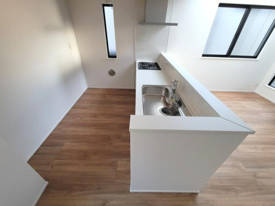 明るい光が差し込むキッチンです。二面採光で空間が開放的に感じられます。カウンター付きで使いやすいレイアウトです。清潔感のあるシンプルなデザインとなっています。