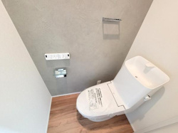 壁付けリモコンが付いており操作がしやすいトイレです。タンク上部には手洗いスペースも設けられています。清潔感のある内装と明るい床材が特徴的です。収納スペースも確保され使い勝手に配慮されています。
