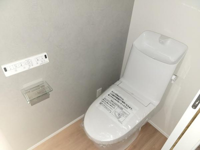 壁付けリモコンが付いており操作がしやすいトイレです。タンク上部には手洗いスペースも設けられています。清潔感のある内装と明るい床材が特徴的です。収納スペースも確保され使い勝手に配慮されています。