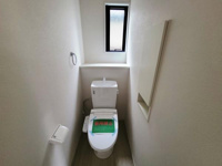 コンパクトなスペースに設置されたトイレです。窓があり換気も可能な設計となっています。シンプルで清潔感のある内装が特徴です。収納スペースもあり使い勝手に配慮されています。