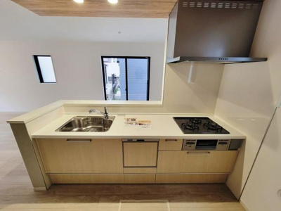 シンプルなデザインが特徴のキッチンです。ワークスペースが広めに確保されています。窓からの採光もあり明るい印象があります。シンクとコンロの配置も使いやすく設計されています。収納スペースも豊富です。