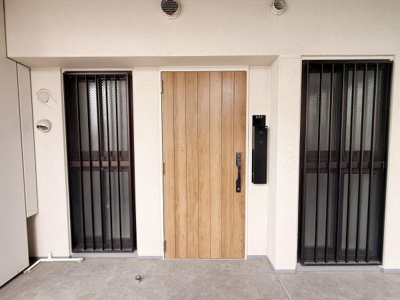 木目調の玄関ドアが印象的でシンプルなデザインが特徴です。両側に設けられた窓には格子が付いており防犯面にも配慮されています。外観全体が明るく清潔感があります。使い勝手の良いスペースが確保されています。