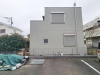 グレーの外壁がスタイリッシュな印象の建物です。窓にはシャッターが設置され防犯面への配慮が感じられます。駐車スペースも確保されており使用しやすい配置です。角地に位置しているため開放感も期待できます。