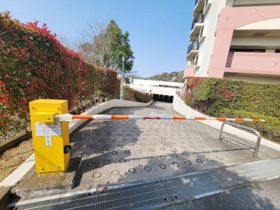駐車場入口にはバーが設置され住民の利便性と安全性が配慮されています。舗装も丁寧で車両の進入がスムーズです。周囲の植栽がしっかり手入れされており明るい印象です。建物も清潔感があります。