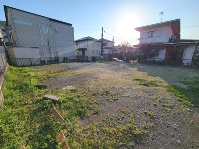 広々とした現地土地写真です。近隣には住宅が立ち並び落ち着いた街並みが感じられます。陽当たりの良い立地で開放感のある空間が広がっています。整形地で使いやすい土地形状も特徴です。
