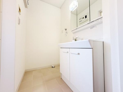 明るい色合いの洗面所は空間全体がすっきりとした印象です。大型の鏡と収納が機能的に配置されています。清潔感のある床材が使用されています。充分なスペースがあり使い勝手の良さが感じられます。