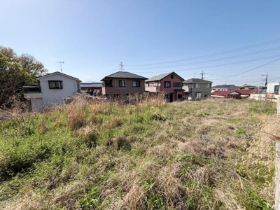 現地土地写真では広々とした敷地が見渡せます。周辺には住宅が建ち並び落ち着いた雰囲気です。草木が生い茂り開放感があります。空が広がり日当たりも期待できます。用途に合わせて活用しやすい土地です。