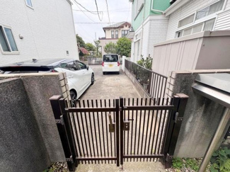 門扉が設置された玄関アプローチで落ち着いた印象を与えます。車の駐車スペースも確保されており日常の使い勝手にも配慮されています。周囲は塀で囲まれているためプライバシー面にも安心感があります。