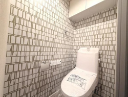 個性的なデザインの壁紙が印象的なトイレです。収納スペースも備え付けられているので使い勝手が良いです。清潔感のある空間が保たれています。落ち着いた雰囲気も感じられます。