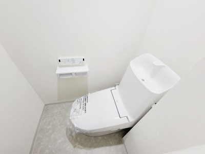 シンプルで清潔感のあるトイレです。操作しやすい壁付けパネルが設置されています。タンク上部には手洗いスペースも付いており便利です。床はお手入れしやすい素材になっています。
