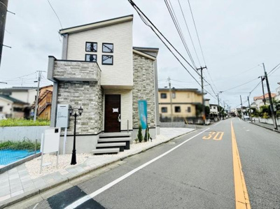 すっきりとした前面道路が印象的な現地写真です。視界が開けており道幅も十分に確保されています。住居の外観はモダンなデザインで落ち着いた雰囲気が感じられます。ゆとりのある歩道スペースも整っています。