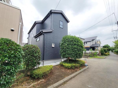 シンプルで落ち着いた色合いの外観が特徴です。周囲の植栽が住まいの魅力を引き立てています。住宅街の中でも存在感のあるデザインが印象的です。道路に面した開放的な立地です。