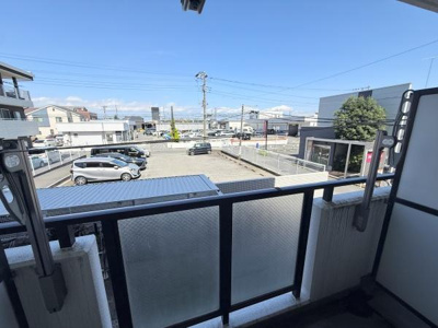 開放感のあるバルコニーからは広々とした駐車場が見渡せます。隣接する建物との距離もあり視界が良好です。ガラスパネルの手すりが空間に明るさをもたらしています。天気の良い日には青空が広がります。