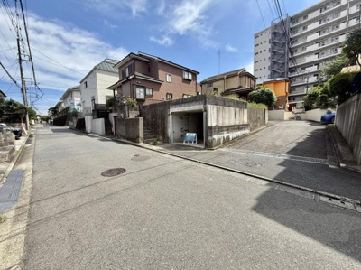 現地写真にはゆったりとした前面道路が写っており周囲は住宅が立ち並ぶ落ち着いた雰囲気です。前面道路は幅員もあり車の出入りがしやすい環境がうかがえます。写真からは周辺の建物や街並みもしっかり確認できます。