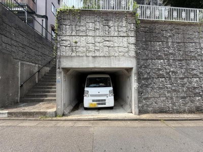 道路に面した位置にあり出入りがしやすい駐車場です。コンクリート造で車両の保護に役立ちます。壁に囲まれているため風雨の影響を受けにくくなっています。階段に隣接しているので歩行者の移動もスムーズです。
