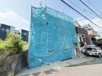 外観は現在工事用の足場とネットで覆われています。敷地は前面道路に面しており周囲には住宅が建ち並んでいます。駐車スペースがある点も特徴です。日当たりの良い位置に建っています。