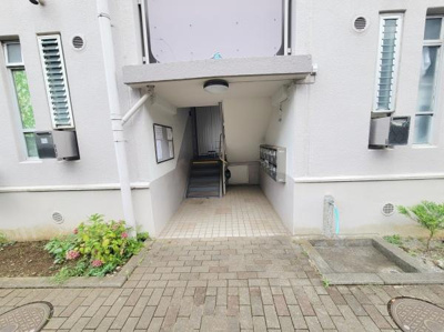 建物のエントランス部分はシンプルで清潔感があります。エントランス周辺は植栽があり落ち着いた雰囲気です。階段や共用設備も見やすく配置されています。ポストもエントランス内に設置されています。