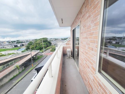 開放感のある広々としたバルコニーが魅力です。レンガ調の外壁がナチュラルな印象を与えています。遠くまで見渡せる眺望が楽しめます。屋根付きで天候に左右されにくいスペースです。