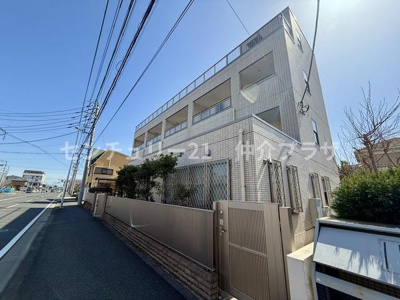 この物件はシンプルな外観が特徴の建物です。道路沿いに位置しアクセスが良好です。ガーデンスペースが程よく配置されており植物が心を和ませます。周囲には建物が多く街の一部として生活を楽しめる環境です。