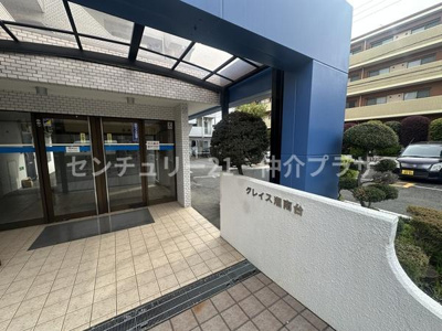 広々としたエントランスが来訪者を温かく迎えます。風雨から守る屋根付きの設計。美しく整えられた植栽が落ち着いた雰囲気を演出しています。