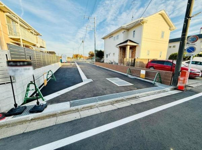 現地と前面道路の様子が一目でわかります。周囲はゆとりある道幅が確保されています。道路面も整備され車の出入りもスムーズです。住宅街の落ち着いた環境が感じられる写真です。