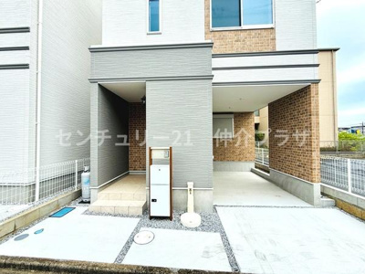 シンプルで清潔感のある玄関スペースが広がっています。屋根付きなので天候に左右されにくく安心です。宅配ボックスが備え付けられており利便性も向上しています。広々としたアプローチが開放的な印象を与えます。